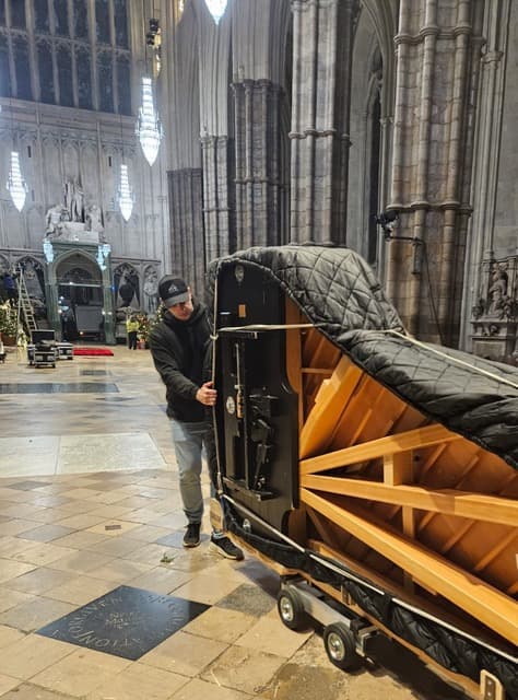 Wrapped grand piano being moved inside a cathedral